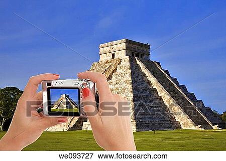 Stock Photo - Caucasian female taking a picture of Chichen Itza The main pyramid El Castillo is also called Temple of Kukulcan The Maya name? Chich? en Itza? means? At the mouth of the well of the Itza? Located in the Yucatan Peninsula of Mexico. Fotosearch