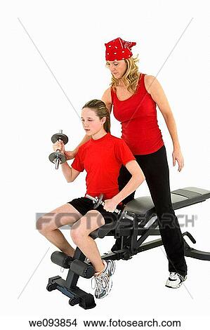 Caucasian mother helping her preteen daughter to lift weights using a dumbbell on a white background View Large Photo Image Picture - Caucasian mother helping her preteen daughter to lift weights using a dumbbell on a white background. Fotosearch
