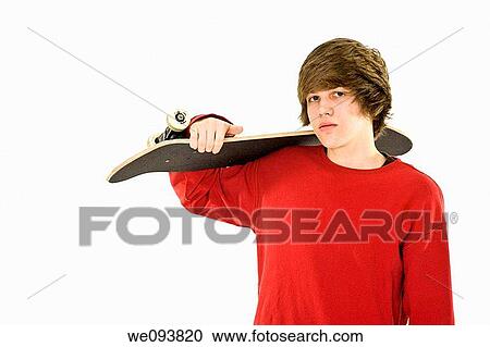 Stock Image - Caucasian teenager holding a skateboard on a white background. Fotosearch
