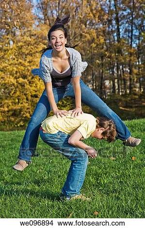 Caucasian teens one male and one female horsing around in a park playing leapfrog View Large Photo Image Picture - Caucasian teens one male and one female horsing around in a park playing leapfrog. Fotosearch