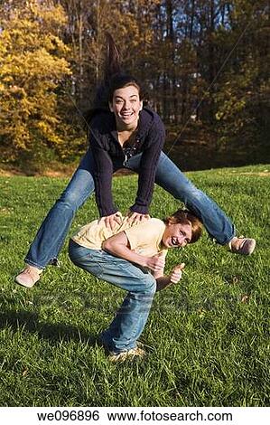 Caucasian teens one male and one female horsing around in a park playing leapfrog View Large Photo Image Stock Photograph - Caucasian teens one male and one female horsing around in a park playing leapfrog. Fotosearch