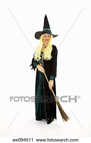 Stock Image - Caucasian woman dressed as a scary witch standing on white background. Fotosearch