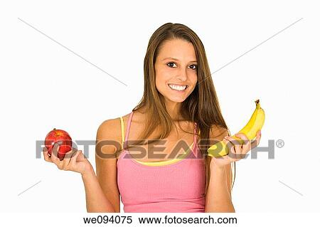 Caucasian woman holding an apple and a banana trying to decide which one to eat View Large Photo Image Stock Photography - Caucasian woman holding an apple and a banana trying to decide which one to eat. Fotosearch