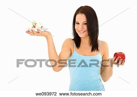 Caucasian woman holding an apple and slice of cake trying to decide which one to eat View Large Photo Image Stock Image - Caucasian woman holding an apple and slice of cake trying to decide which one to eat. Fotosearch
