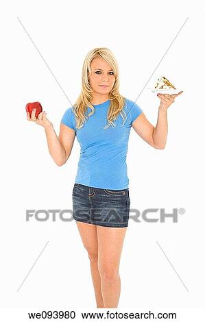 Caucasian woman holding an apple and slice of cake trying to decide which one to eat View Large Photo Image Stock Image - Caucasian woman holding an apple and slice of cake trying to decide which one to eat. Fotosearch