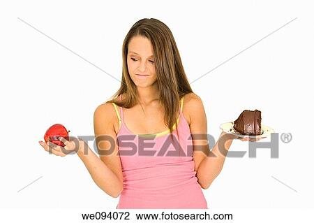 Caucasian woman holding an apple and slice of chocolate cake trying to decide which one to eat View Large Photo Image Stock Image - Caucasian woman holding an apple and slice of chocolate cake trying to decide which one to eat. Fotosearch