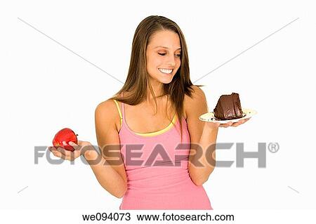 Caucasian woman holding an apple and slice of chocolate cake trying to decide which one to eat View Large Photo Image Stock Image - Caucasian woman holding an apple and slice of chocolate cake trying to decide which one to eat. Fotosearch