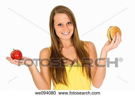 Caucasian woman holding an apple and hambuger trying to decide which one to eat View Large Photo Image Stock Image - Caucasian woman holding an apple and hambuger trying to decide which one to eat. Fotosearch