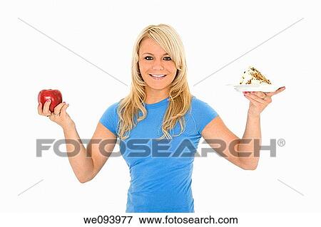 Caucasian woman holding an apple and slice of cake trying to decide which one to eat View Large Photo Image Stock Photo - Caucasian woman holding an apple and slice of cake trying to decide which one to eat. Fotosearch