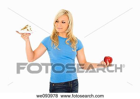 Caucasian woman holding an apple and slice of cake trying to decide which one to eat View Large Photo Image Stock Photo - Caucasian woman holding an apple and slice of cake trying to decide which one to eat. Fotosearch
