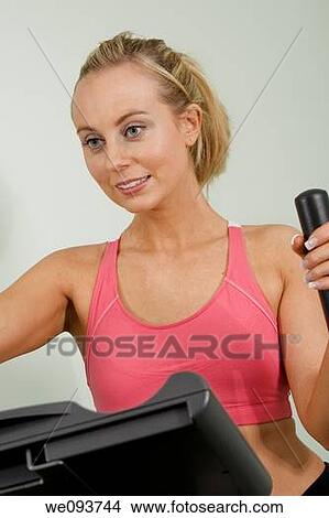 Caucasian woman in early 20s exercising on a cardiovascular machine View Large Photo Image Picture - Caucasian woman in early 20s exercising on a cardiovascular machine. Fotosearch