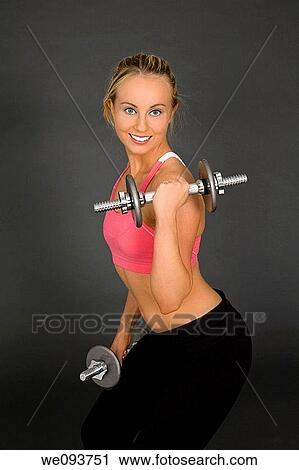 Caucasian woman in early 20s lifting weights using a dumbbell on a gray background View Large Photo Image Stock Image - Caucasian woman in early 20s lifting weights using a dumbbell on a gray background. Fotosearch