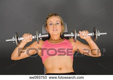 Caucasian woman in early 20s lifting weights using a dumbbell on a gray background View Large Photo Image Stock Image - Caucasian woman in early 20s lifting weights using a dumbbell on a gray background. Fotosearch