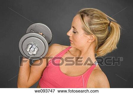 Caucasian woman in early 20s lifting weights using a dumbbell on a gray background View Large Photo Image Stock Photo - Caucasian woman in early 20s lifting weights using a dumbbell on a gray background. Fotosearch