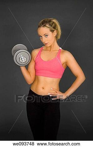 Caucasian woman in early 20s lifting weights using a dumbbell on a gray background View Large Photo Image Stock Photo - Caucasian woman in early 20s lifting weights using a dumbbell on a gray background. Fotosearch