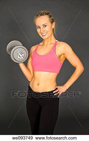 Caucasian woman in early 20s lifting weights using a dumbbell on a gray background View Large Photo Image Stock Photo - Caucasian woman in early 20s lifting weights using a dumbbell on a gray background. Fotosearch