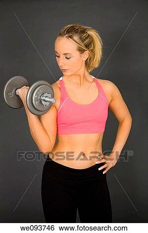 Caucasian woman in early 20s lifting weights using a dumbbell on a gray background View Large Photo Image Stock Photograph - Caucasian woman in early 20s lifting weights using a dumbbell on a gray background. Fotosearch