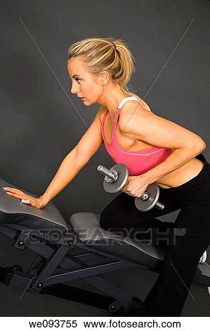 Caucasian woman in early 20s lifting weights using a dumbbell on a gray background View Large Photo Image Stock Photography - Caucasian woman in early 20s lifting weights using a dumbbell on a gray background. Fotosearch