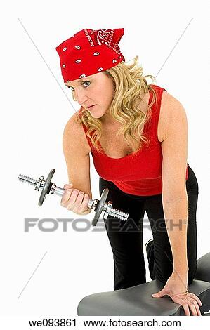Stock Image - Caucasian woman in early 40s lifting weights using a dumbbell on a white background. Fotosearch