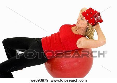 Stock Photo - Caucasian woman in early 40s using a excerise ball andl on a white background. Fotosearch