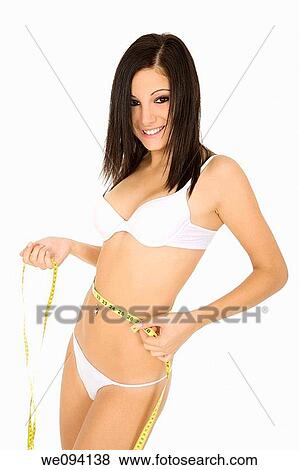 Stock Photo - Caucasian woman measuring her waist on a white background. Fotosearch