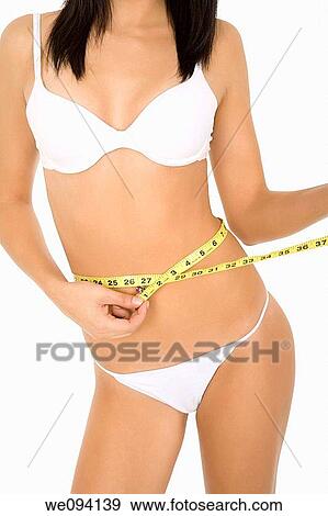Stock Photo - Caucasian woman measuring her waist on a white background. Fotosearch