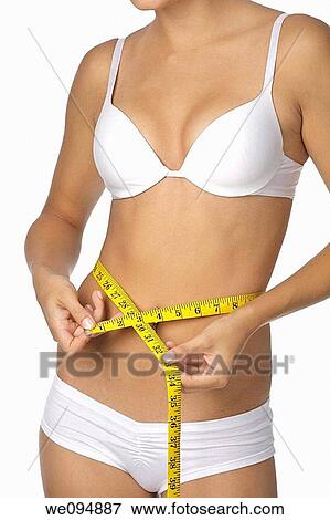 Caucasian woman measuring her waist on a white background View Large Photo Image Stock Photo - Caucasian woman measuring her waist on a white background. Fotosearch