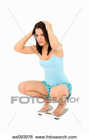 Caucasian woman standing on a scale weighting herself and very upset View Large Photo Image Stock Photograph - Caucasian woman standing on a scale weighting herself and very upset. Fotosearch