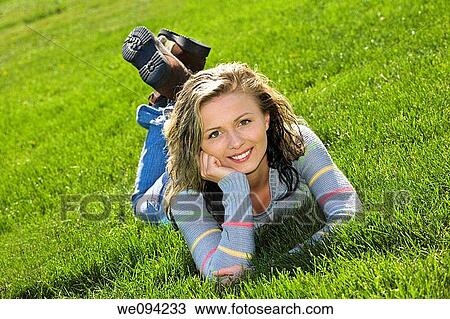 Stock Image - Caucasion teenage girl laying in the grass and smiling. Fotosearch