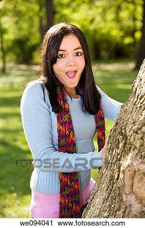 Caucasion teenage girl looking out from behind a tree and smiling View Large Photo Image Stock Image - Caucasion teenage girl looking out from behind a tree and smiling. Fotosearch