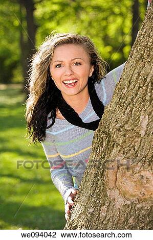 Caucasion teenage girl looking out from behind a tree and smiling View Large Photo Image Stock Image - Caucasion teenage girl looking out from behind a tree and smiling. Fotosearch