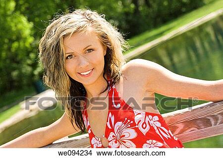 Picture - Caucasion teenage girl standing on bridge in a park and smiling. Fotosearch