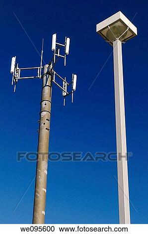 Cell phone communications tower against a blue sky with a lamp post View Large Photo Image Stock Image - Cell phone communications tower against a blue sky with a lamp post. Fotosearch