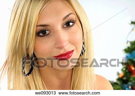 Close up of a smiling young blond woman standing by a Christmas tree View Large Photo Image Stock Image - Close up of a smiling young blond woman standing by a Christmas tree. Fotosearch