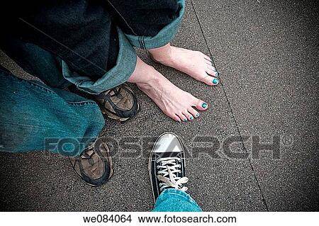 Close-up of a young couple's legs and feet next to a man's foot View Large Photo Image Picture - Close-up of a young couple's legs and feet next to a man's foot. Fotosearch
