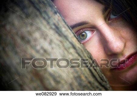 Close-up of a young woman behind a tree. View Large Photo Image Stock Photo - Close-up of a young woman behind a tree.. Fotosearch