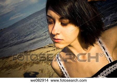 Close-up of a young woman standing by the ocean. View Large Photo Image Picture - Close-up of a young woman standing by the ocean.. Fotosearch