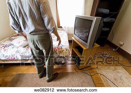 Stock Image - Close_up of a man standing in a bedroom.. Fotosearch