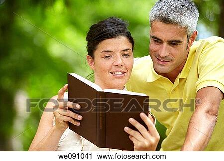 Couple reading a book in a garden, spa, Lierganes, Cantabria, Spain View Large Photo Image Stock Image - Couple reading a book in a garden, spa, Lierganes, Cantabria, Spain. Fotosearch