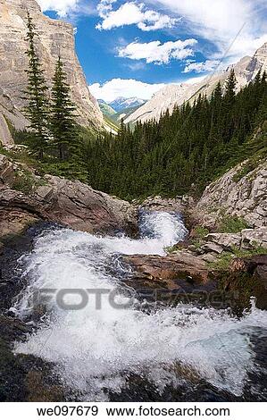 Stock Photo - curved creek in foreground with mountain range in background, with sky. Fotosearch