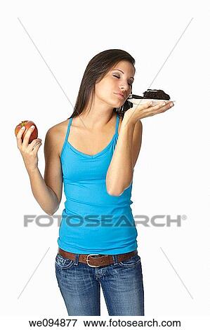 Stock Photo - Cute Caucasian woman trying to make a decision between eating healthy or not. Fotosearch
