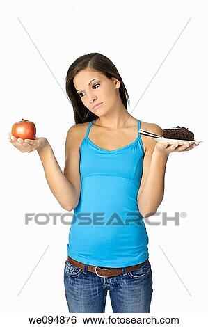 Cute Caucasian woman trying to make a decision between eating healthy or not View Large Photo Image Stock Photograph - Cute Caucasian woman trying to make a decision between eating healthy or not. Fotosearch