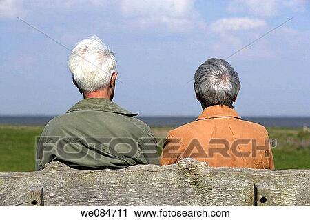 Elderly couple sitting on a bench and seen from backside, Island of Amrum, North Frisian Islands, Schleswig-Holstein, Northern Germany View Large Photo Image Stock Image - Elderly couple sitting on a bench and seen from backside, Island of Amrum, North Frisian Islands, Schleswig-Holstein, Northern Germany. Fotosearch