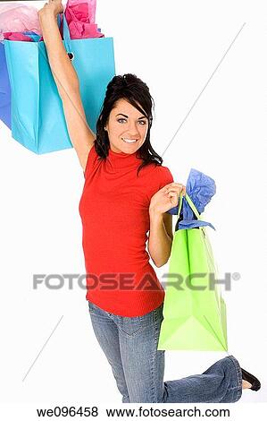 Excited Caucasian woman holding shopping bags and smiling on white background View Large Photo Image Stock Photo - Excited Caucasian woman holding shopping bags and smiling on white background. Fotosearch
