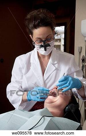 Stock Photo - Female dental professional performing a dental exam on a patient. Fotosearch