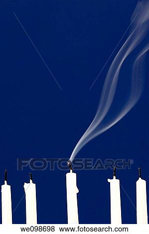 Five white candles that have just been blown out, with smoke rising from the center candle against a blue background The wick is still red hot View Large Photo Image Stock Photo - Five white candles that have just been blown out, with smoke rising from the center candle against a blue background The wick is still red hot. Fotosearch