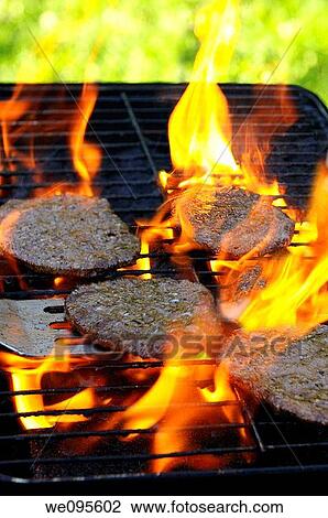 Flaming burgers burning on an outdoor grill at a picnic in the park View Large Photo Image Stock Image - Flaming burgers burning on an outdoor grill at a picnic in the park. Fotosearch