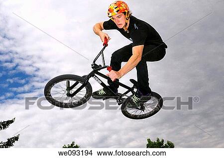 Grimacing BMX bike rider in the air doing an Air Out Tabletop move against a cloudy sky View Large Photo Image Picture - Grimacing BMX bike rider in the air doing an Air Out Tabletop move against a cloudy sky. Fotosearch