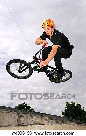 Grimacing BMX bike rider in the air doing an Air Out Tabletop move off a concrete wall View Large Photo Image Stock Image - Grimacing BMX bike rider in the air doing an Air Out Tabletop move off a concrete wall. Fotosearch