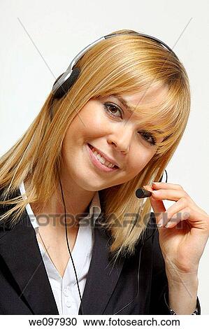 Stock Image - Happy blonde business woman with headset working in a call centre. Fotosearch
